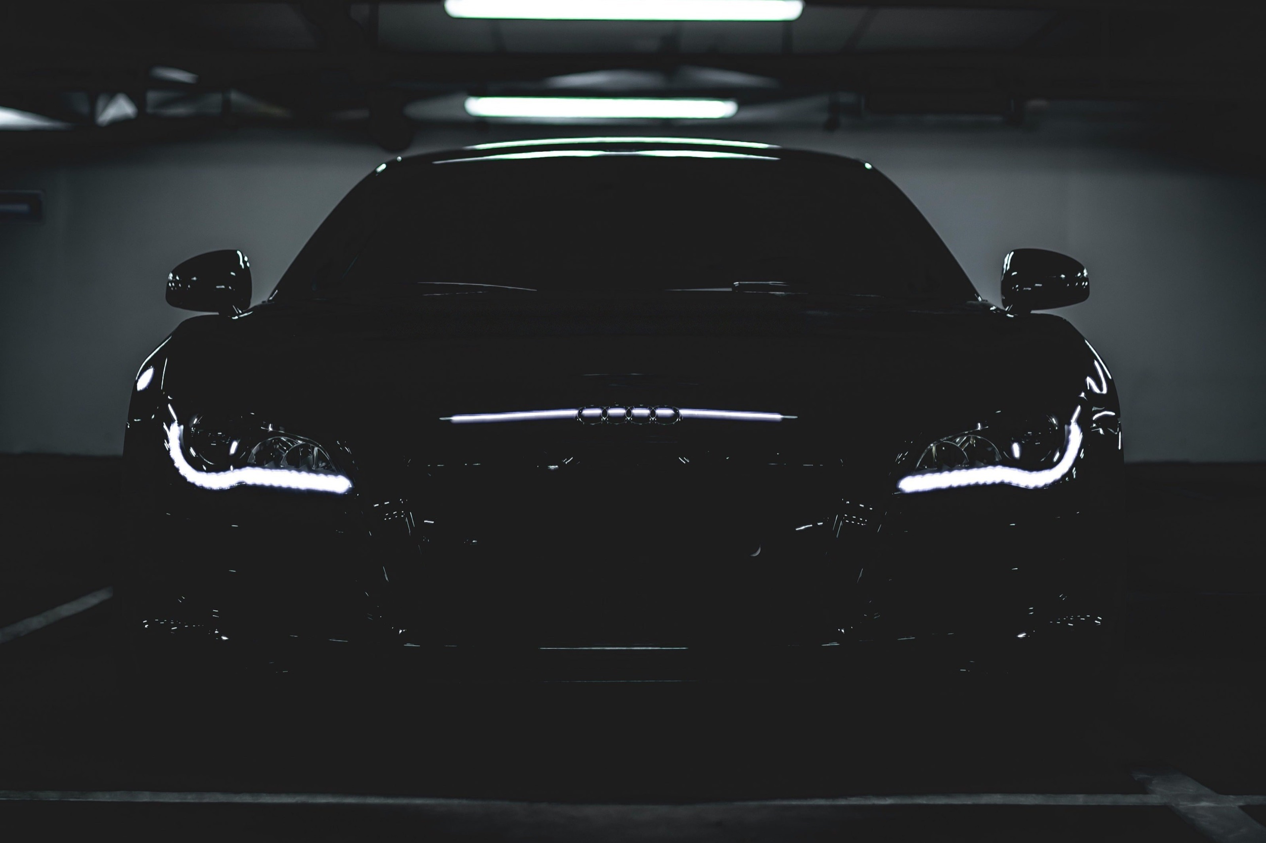 Black Audi R8 with its headlights on in a dark garage
